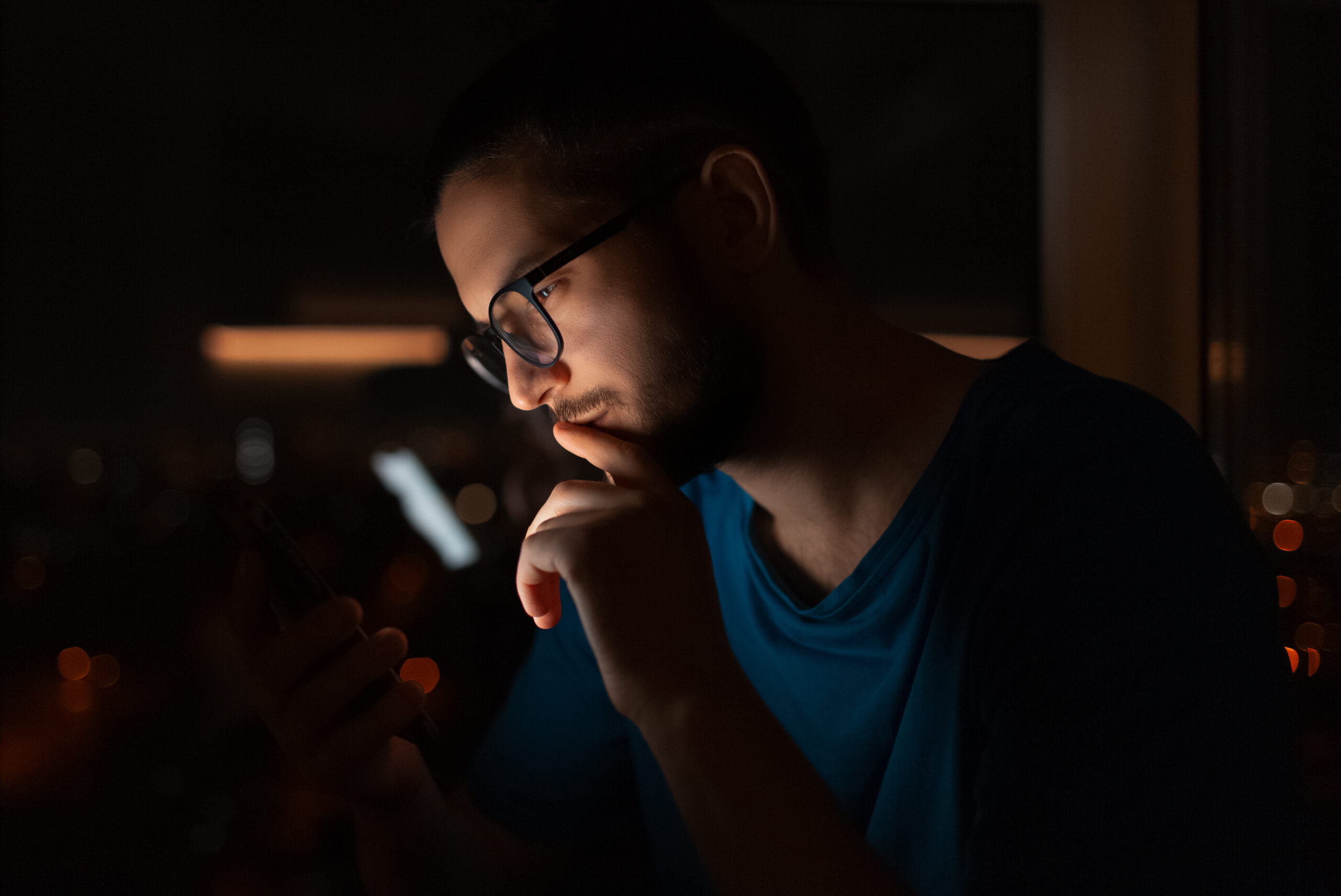 serious man looking at smartphone in dark room