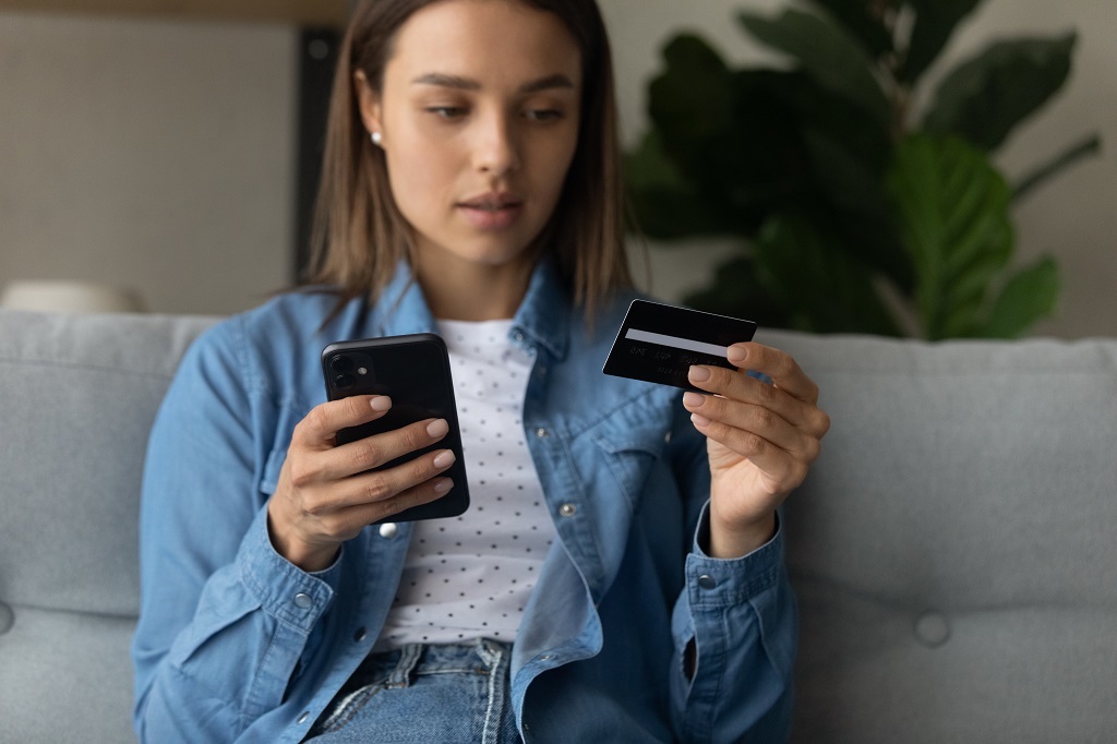 Young lady making purchase at internet shop using cellphone.