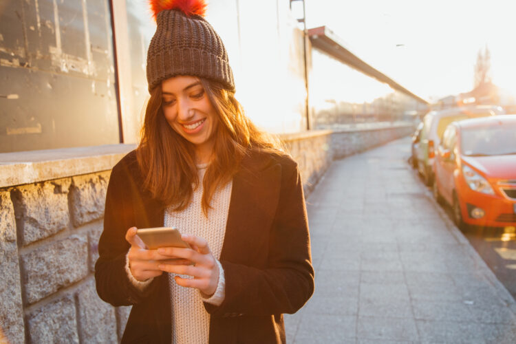 Happy young woman with her mobile on the street