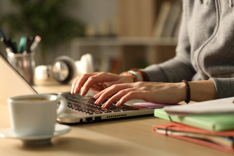 hands typing on laptop at desk.