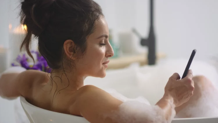 woman using smartphone in bathtub.
