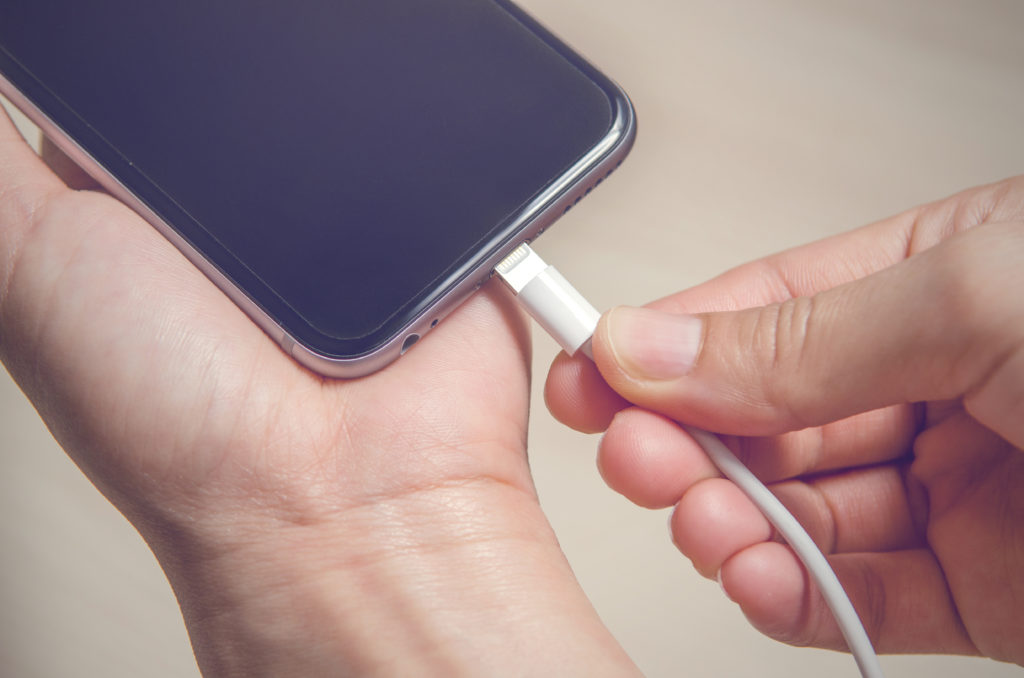 Hands holding a phone charger.