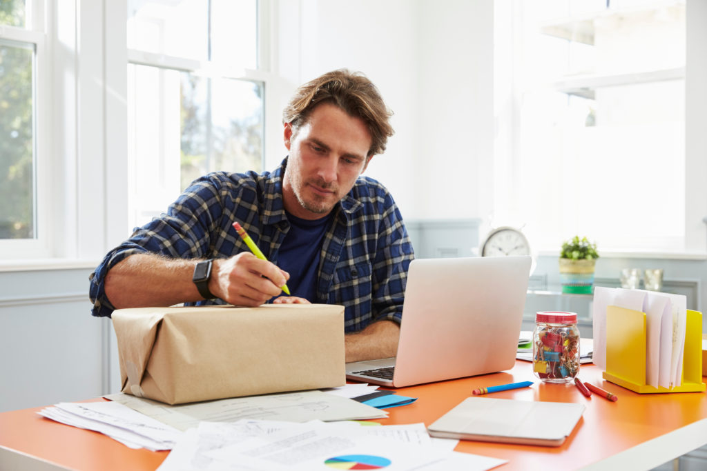 Man writing address on the parcel.