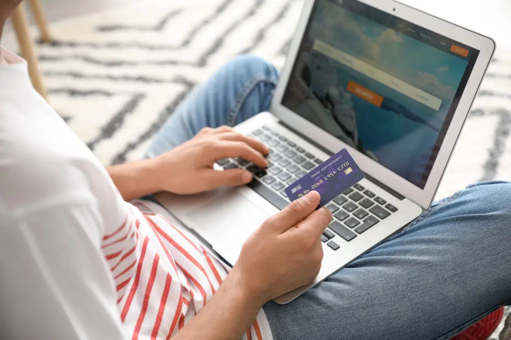 Woman using a laptop in booking tickets online with credit card demonstrating a common business application of ICT or IT.