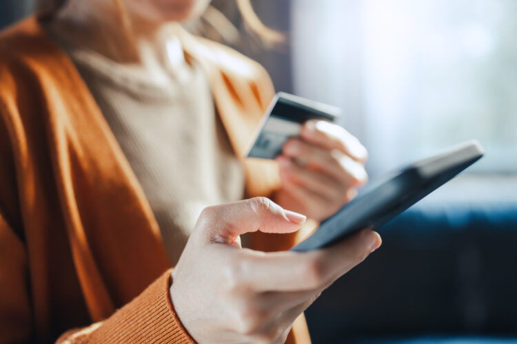 woman holding a credit card making an online payment on her phone.