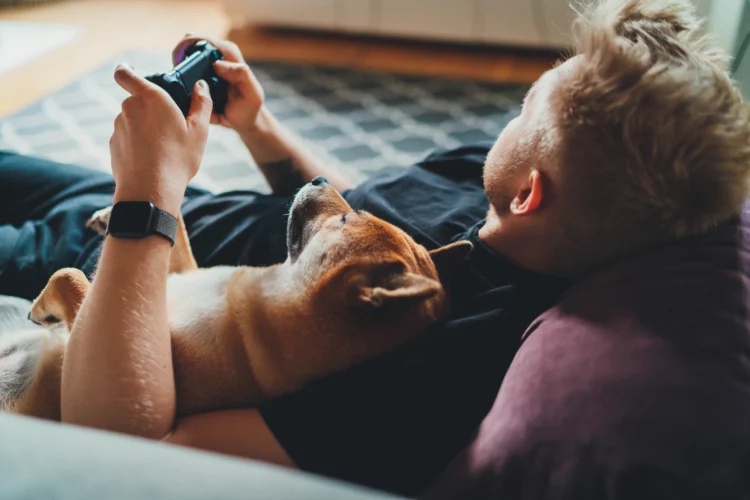 Young hipster guy playing video games at home holding game joystick