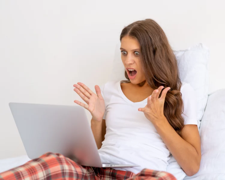 Female angry and shocked looking at her laptop.