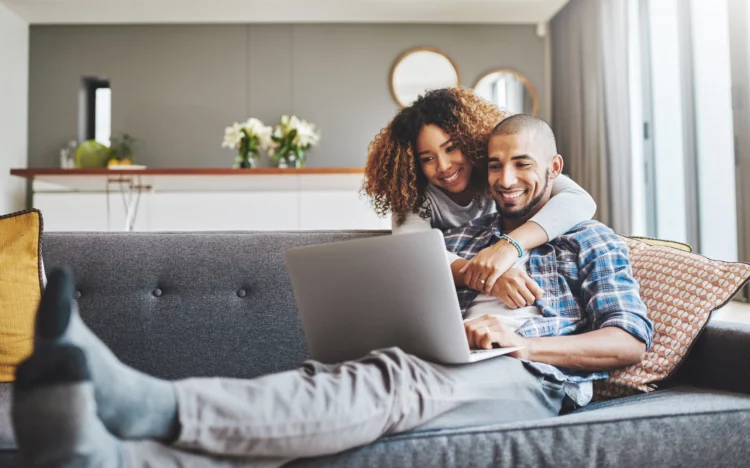 couple hug each other while watching something on the laptop
