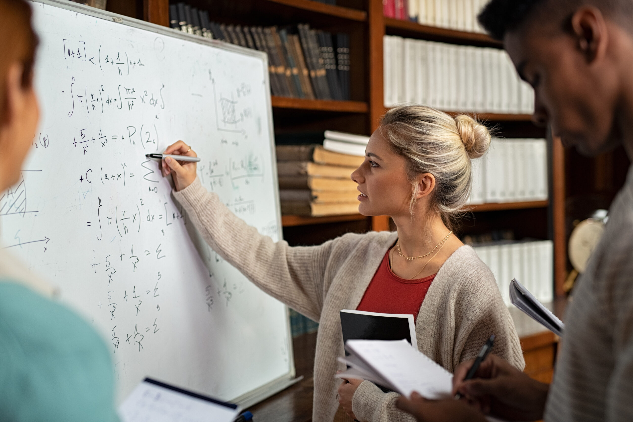 College students solving math on whiteboard