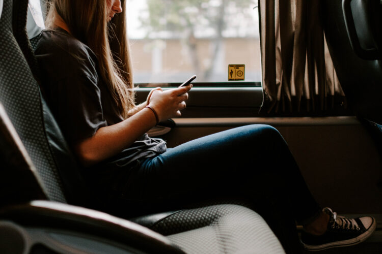 Young woman on a bus using her phone.