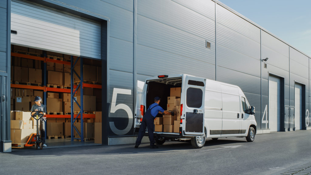 Outside of logistics warehouse, van loading packages