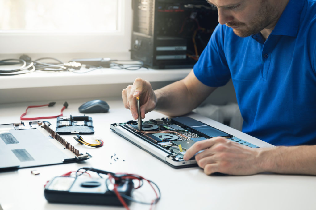 computer repair service - technician repairing broken laptop.