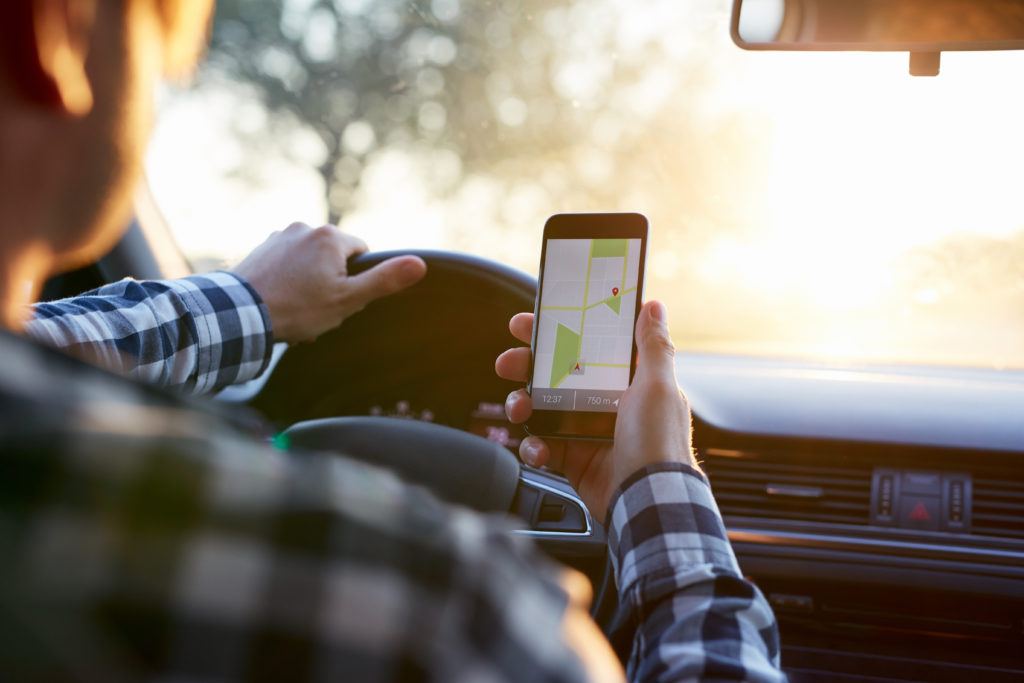 Man in the car holding mobile phone with map gps navigation