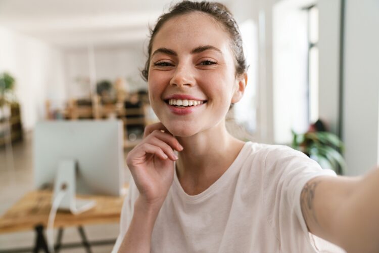 Young brunette woman casually dressed smiling at the camera taking a selfie