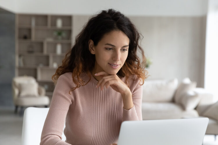 Smiling young hispanic woman working on computer at home.