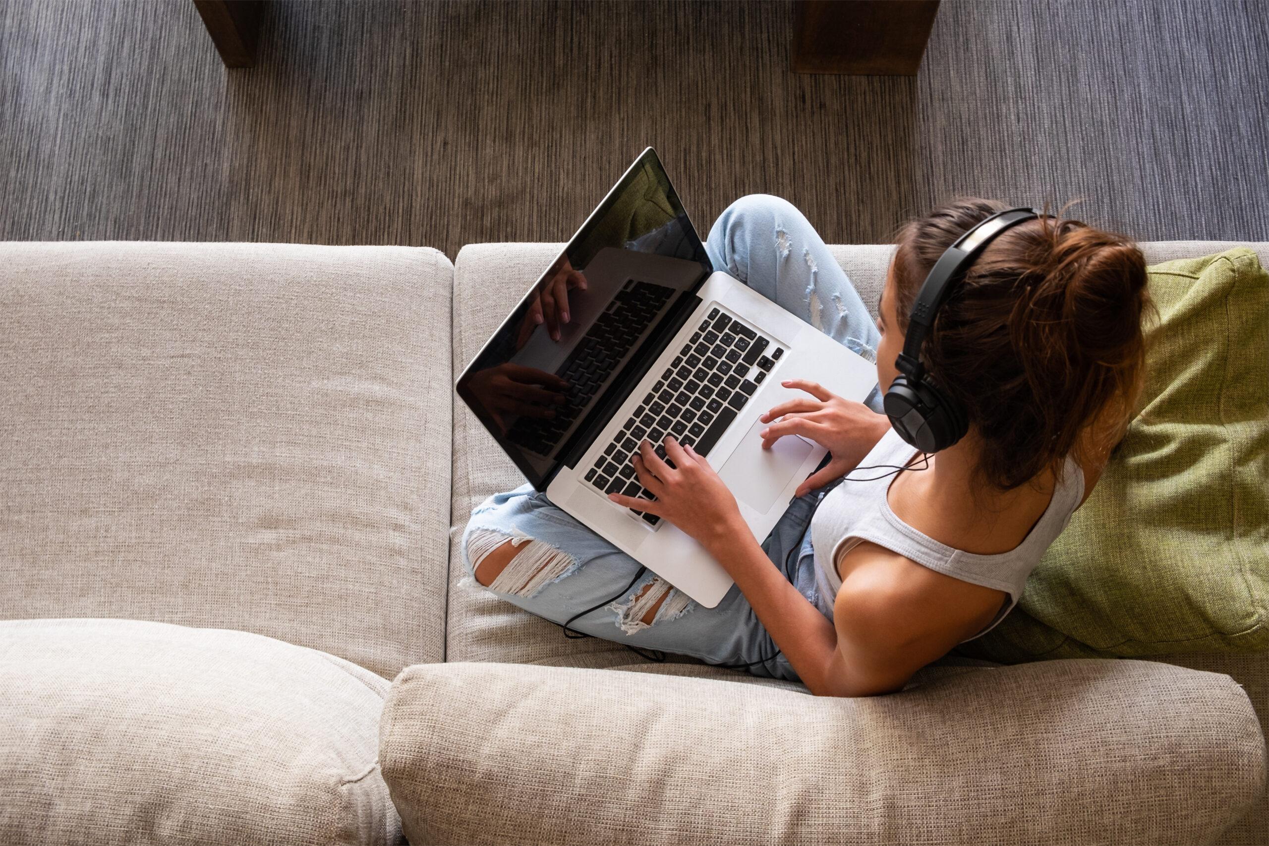 vista superior de una joven que trabaja con una laptop y escucha música