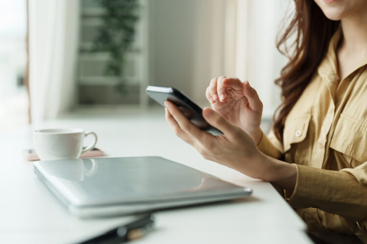 female hand using cellphone at desk