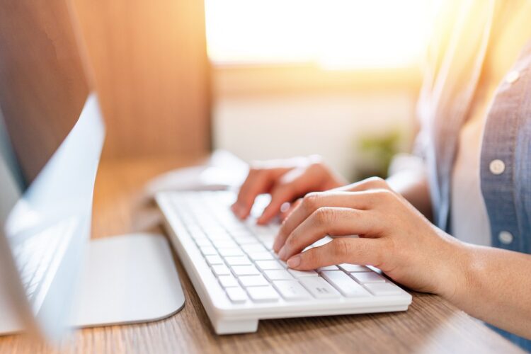 woman's hands typing on desktop computer keyboard at office