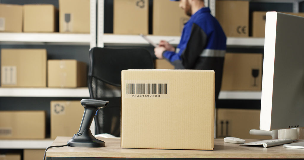 Carton box with bar code is on table at computer in an Amazon warehouse that says arriving today by 10pm but not shipped.