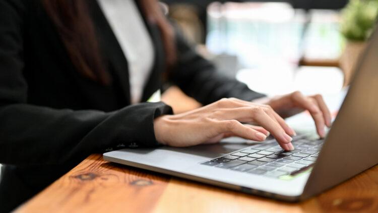 female office worker working on laptop computer, typing on keyboard