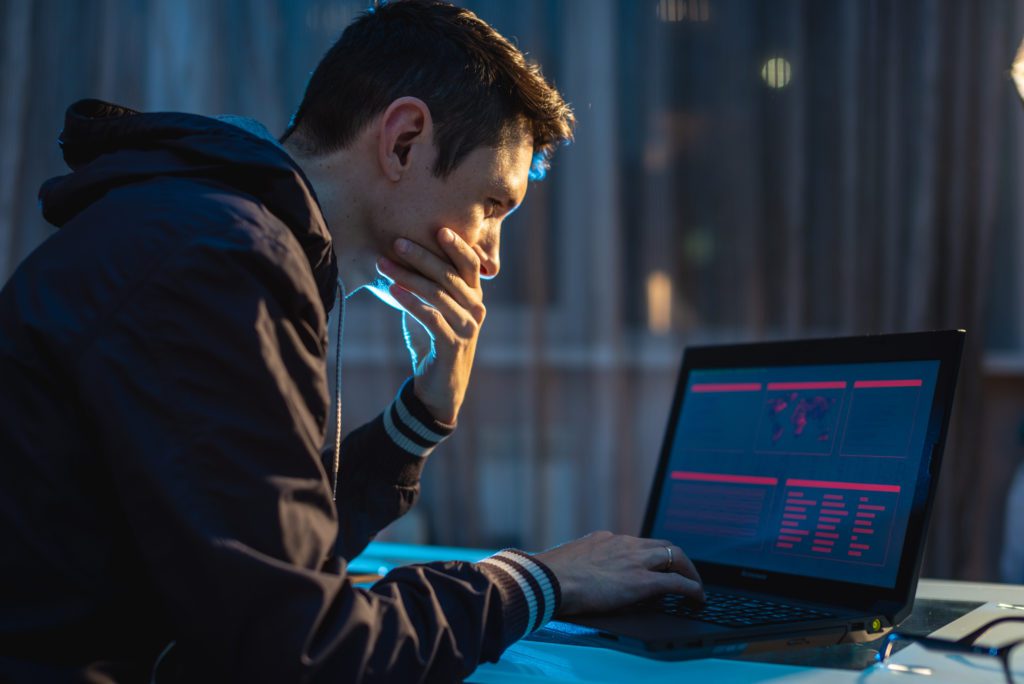 Male hacker thinking about the problem of stealing access to a database.