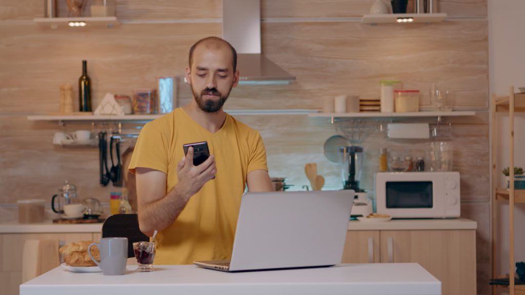 Man with laptop in kitchen with automated lighting system.