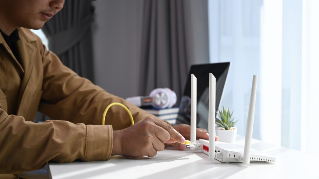 Close up view of young man connecting the internet cable into a router.