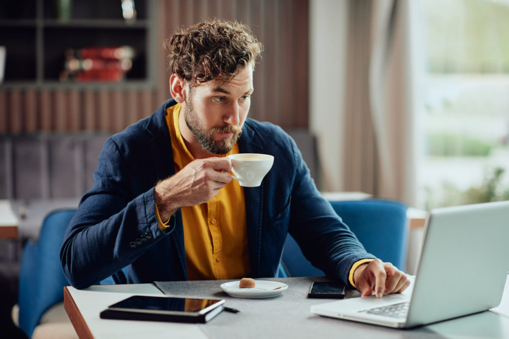 Entrepreneur drinking espresso and using laptop in coffee shop.