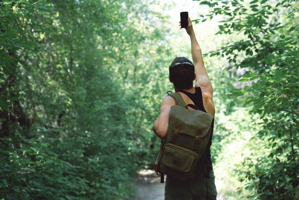 Man in a forest with his phone having no signal.