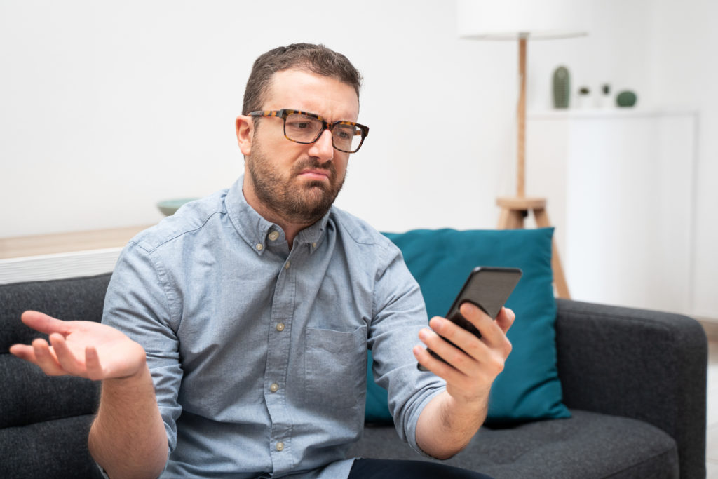 Frustrated man looking at his broken smartphone.