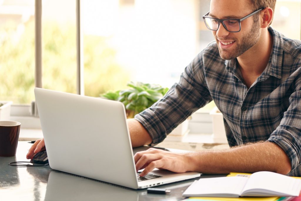 Man using his white laptop while working on the table.