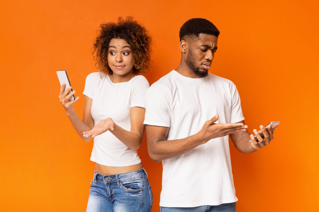 Man and woman with disappointed look, holding their smartphones.