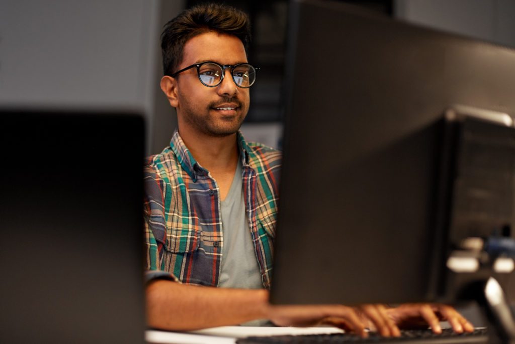 Creative man with dual monitors working in the office at night.