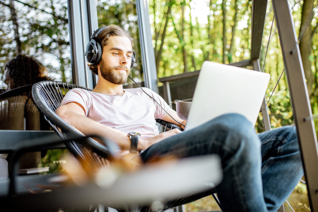 Man working on his laptop while sitting at the house balcony.