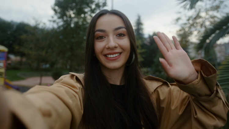 Beautiful young smiling face woman looking at camera holding phone in hand