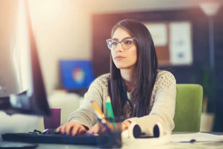 Woman sitting in the office at desk working on how to copy files off a computer without leaving a trace.