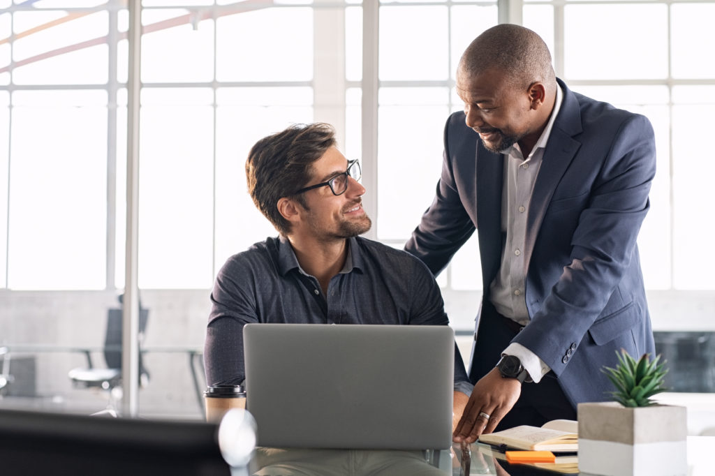 Mature executive helping new employee on a task.