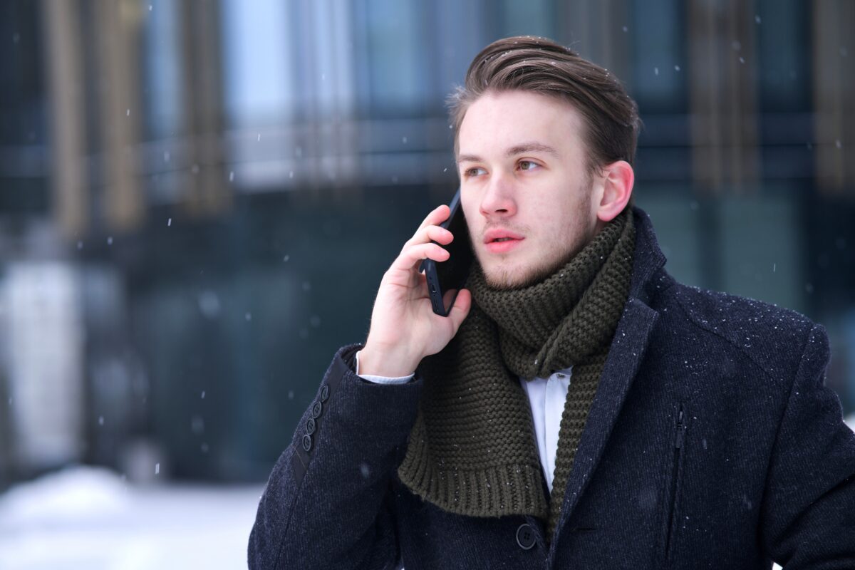Serious handsome man talking on his mobile phone outdoors on a snowy day.