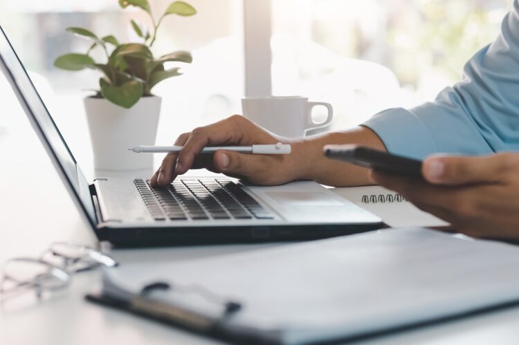 Worker using mobile phone while working on computer