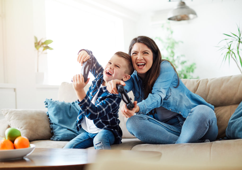 Mutter und Sohn spielen Konsolenspiele zu Hause.