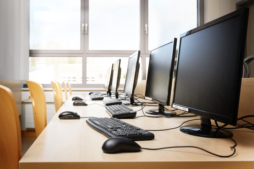 Empty computer room with monitors and keyboards in a row.