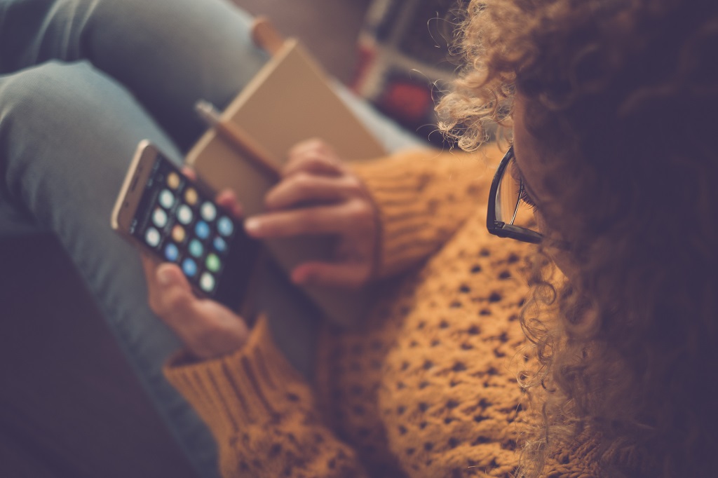 A woman viewed from above using a smartphone with various apps.