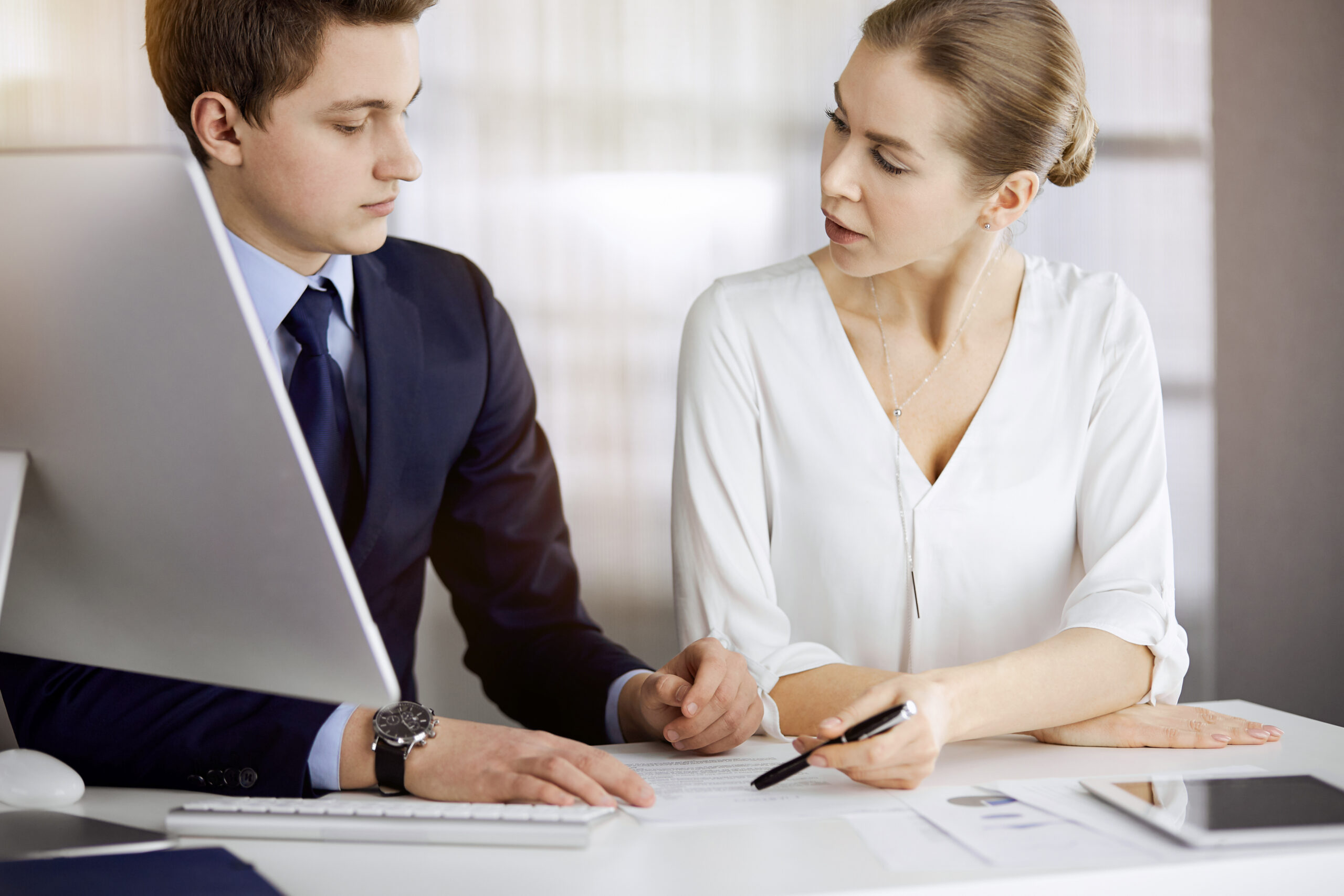 Business people discussing something while sitting in sunny office. Focus at businesswoman while talking to her male colleague