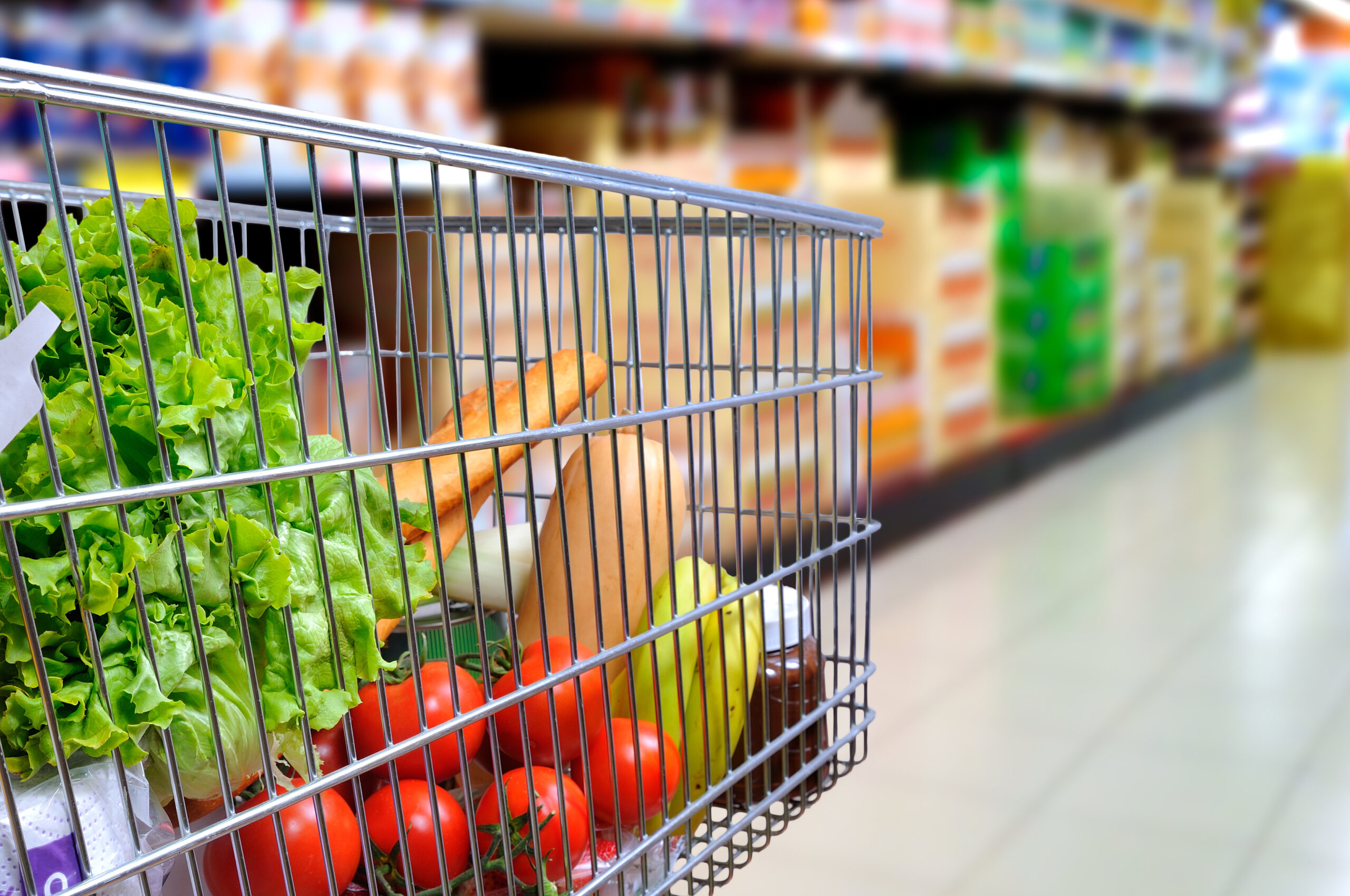 shopping cart full of groceries in supermarket aisle