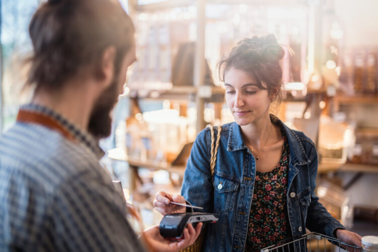 A  young woman makes a contactless card payment in a store