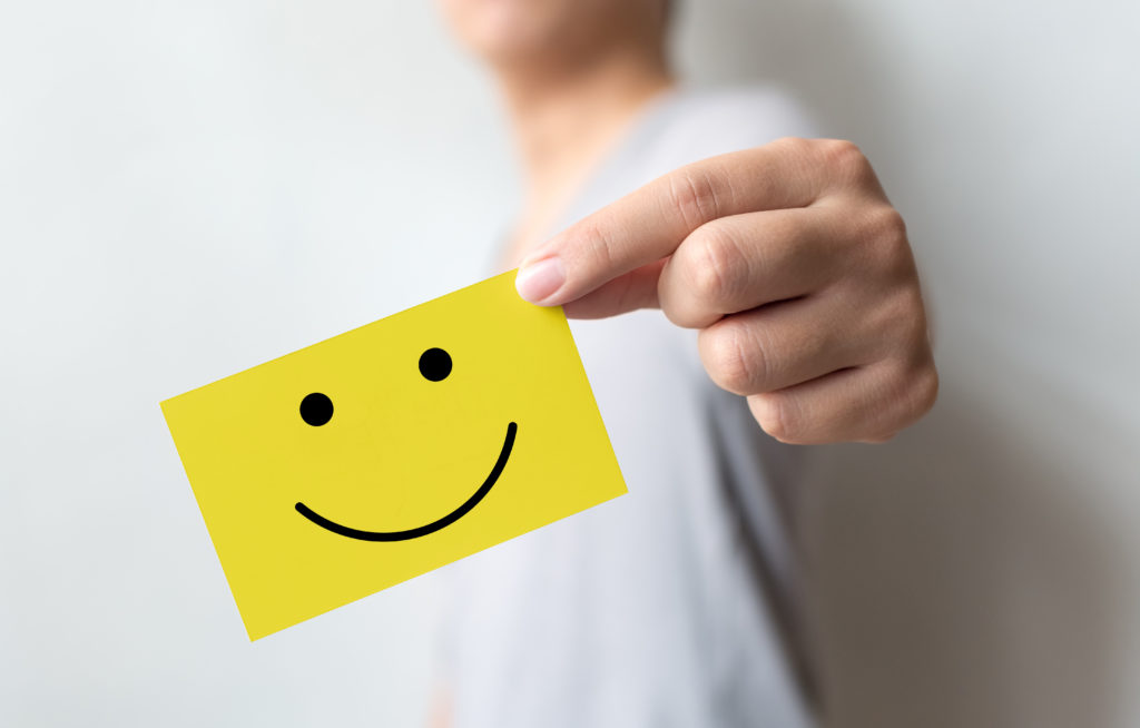 Customer service experience and business satisfaction survey. Man holding yellow card with smiley face.