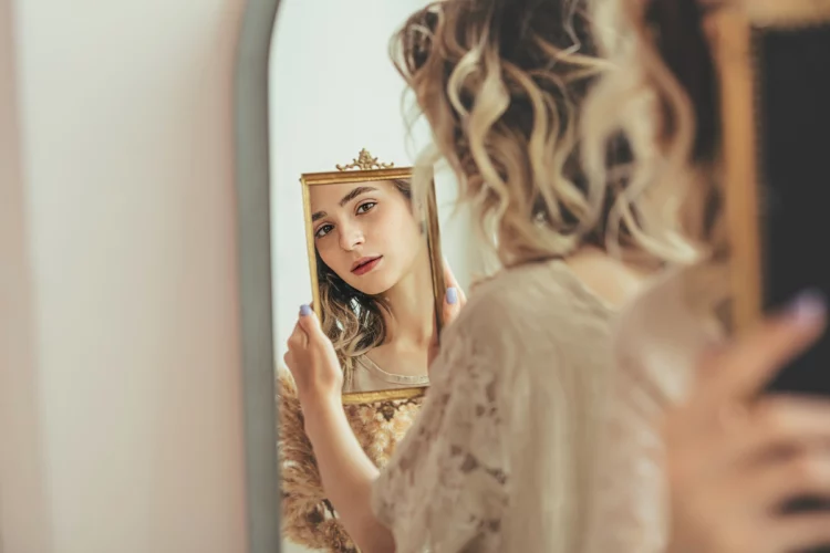 Young beautiful woman with natural makeup looks at her reflection in the mirror