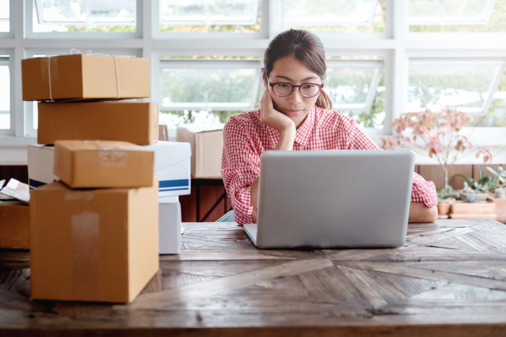 Online shop owner checking through inventories on her laptop.