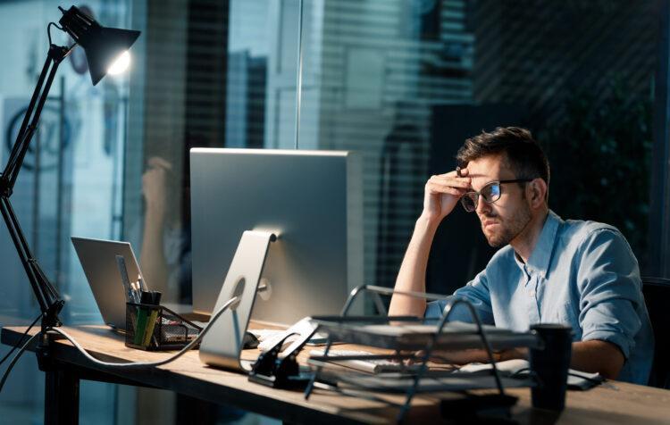 young computer programmer alone in his office looking sad