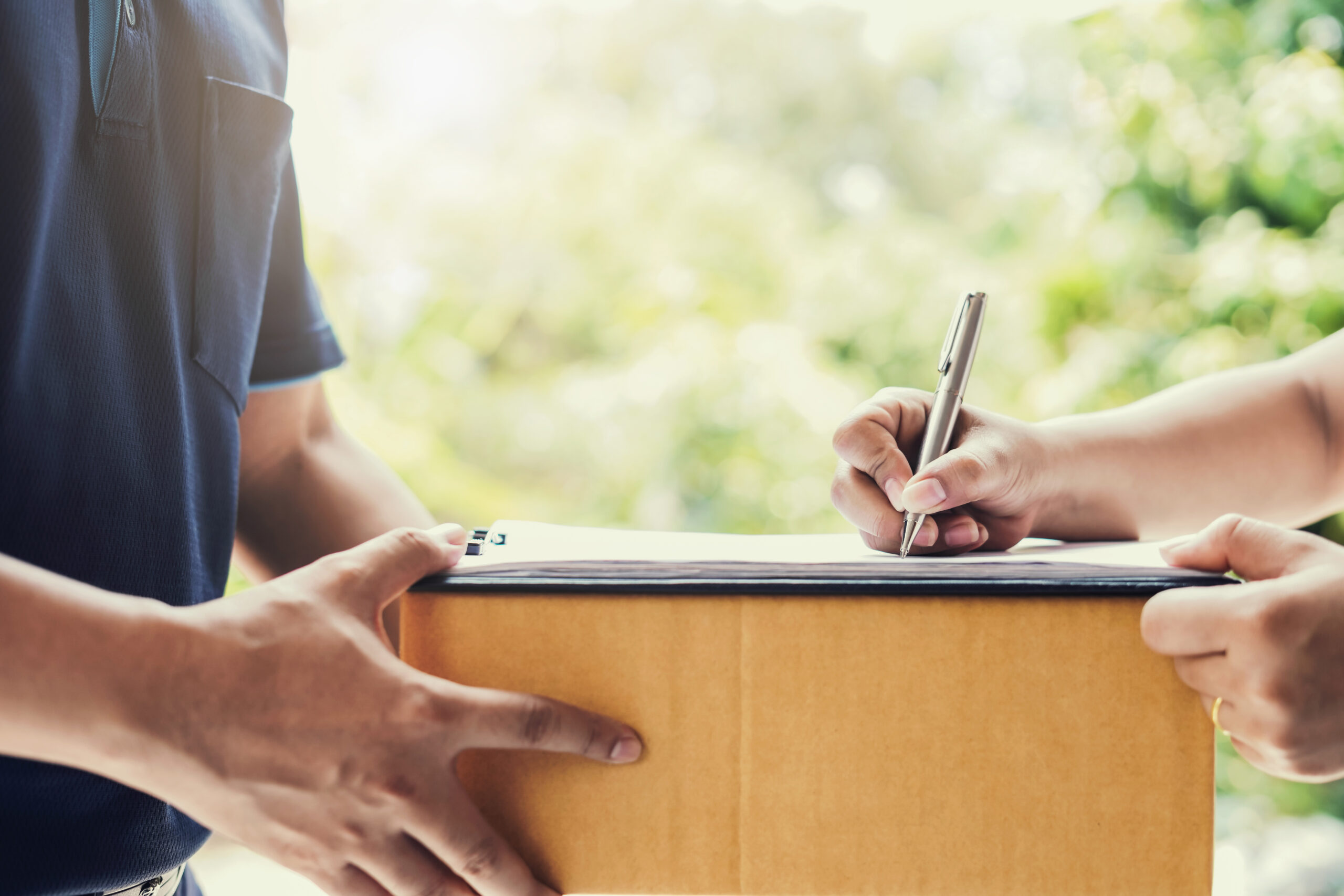 woman signs on paper for receiving parcel